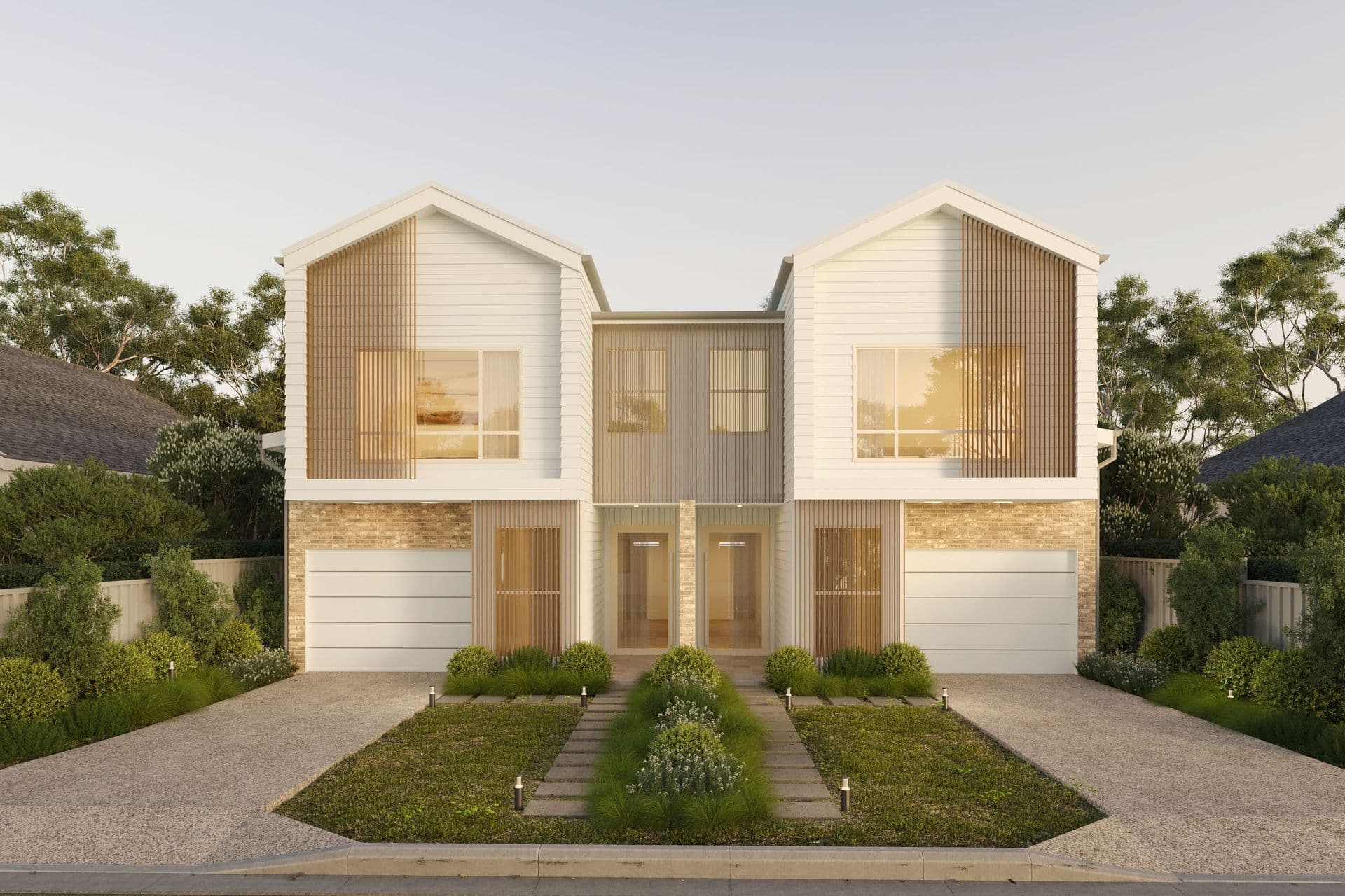 Dusk exterior view of a dual-occupancy duplex in Balgownie, NSW, showing warm interior lighting through timber-and-stone-clad facades